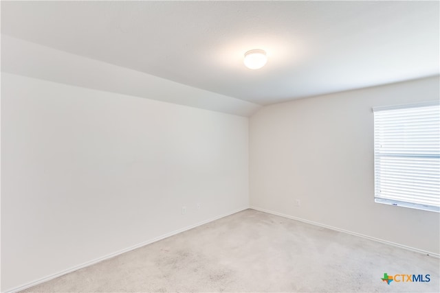 carpeted spare room with lofted ceiling