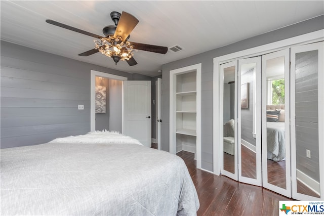 bedroom with dark hardwood / wood-style flooring, ceiling fan, and multiple closets