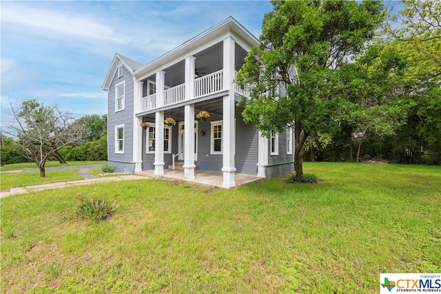 neoclassical home with a balcony, a front yard, and covered porch