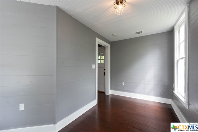 spare room featuring wood walls and dark hardwood / wood-style floors