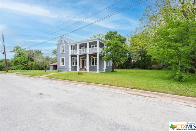 greek revival inspired property with covered porch and a front yard