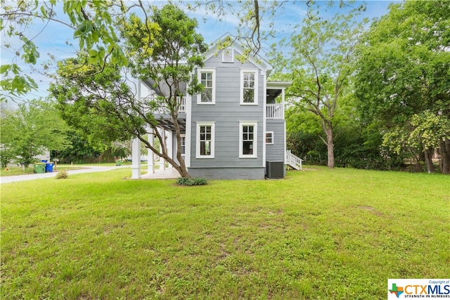 view of side of home featuring a balcony, central AC unit, and a yard