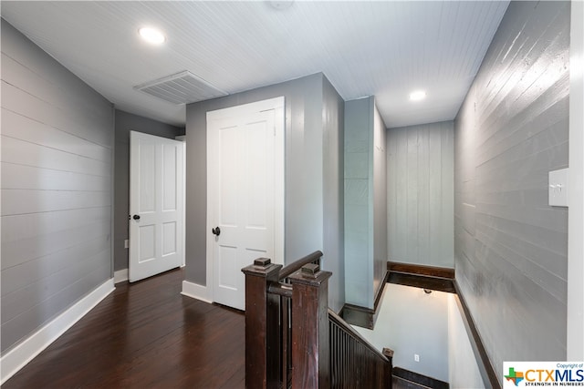 corridor featuring dark hardwood / wood-style flooring and wood walls