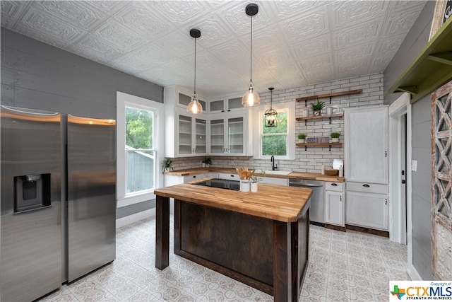 kitchen featuring stainless steel appliances, white cabinets, sink, butcher block countertops, and decorative light fixtures