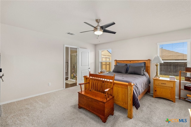 carpeted bedroom with ensuite bath and ceiling fan