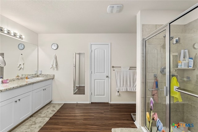 bathroom with hardwood / wood-style floors, an enclosed shower, vanity, and a textured ceiling