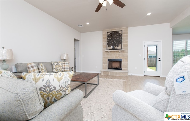 living room with a fireplace, ceiling fan, and light hardwood / wood-style flooring