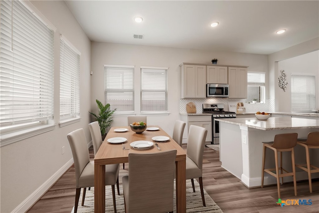 kitchen with visible vents, wood finished floors, backsplash, and appliances with stainless steel finishes