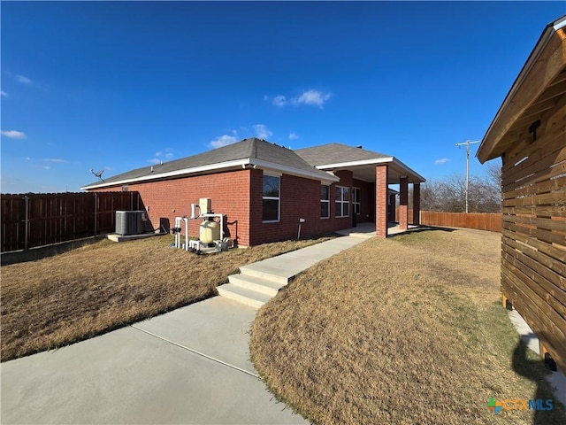 back of property featuring central AC, a patio area, and a yard