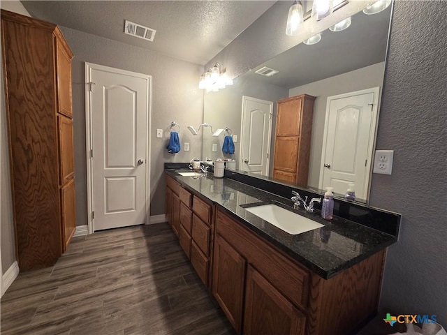 bathroom with hardwood / wood-style flooring, a textured ceiling, and vanity