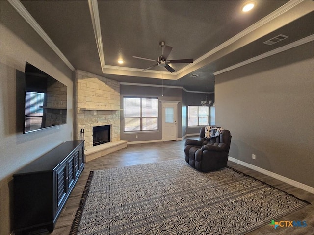 living room featuring crown molding, a fireplace, and a tray ceiling