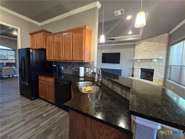 kitchen with dark stone countertops, black appliances, sink, crown molding, and hanging light fixtures