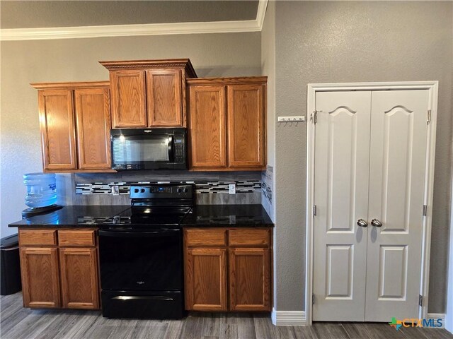 kitchen featuring black appliances, decorative backsplash, crown molding, and hardwood / wood-style flooring