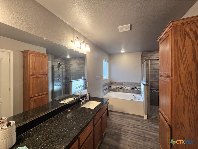 bathroom featuring hardwood / wood-style flooring, a textured ceiling, vanity, and shower with separate bathtub