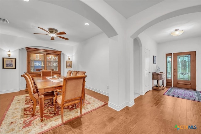 dining room featuring ceiling fan, arched walkways, light wood-style floors, and visible vents