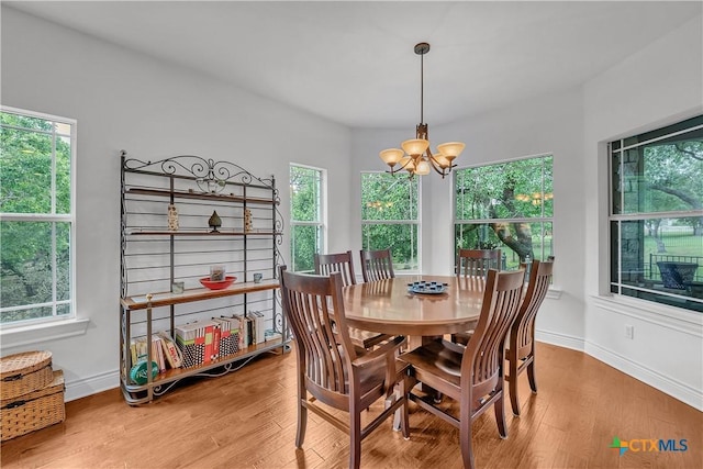 dining space with an inviting chandelier, wood finished floors, and baseboards