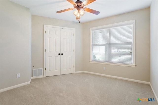 unfurnished bedroom with ceiling fan, light colored carpet, and a closet