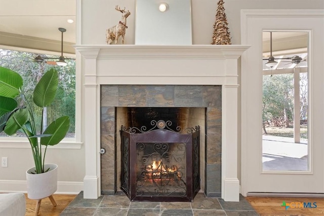 room details with a tile fireplace, wood-type flooring, and ceiling fan