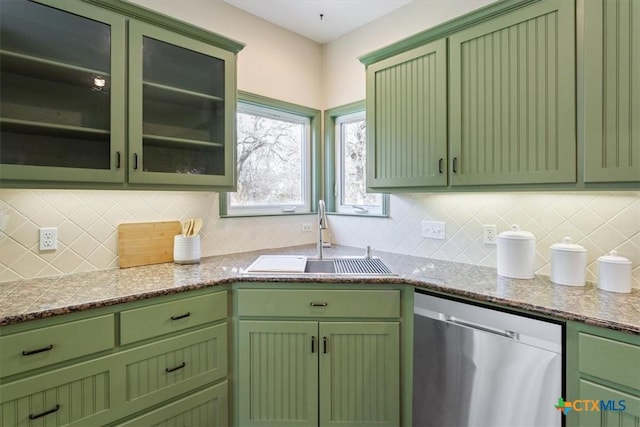 kitchen with dishwasher, sink, green cabinets, light stone counters, and backsplash