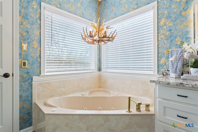 bathroom featuring vanity, tiled bath, and a notable chandelier