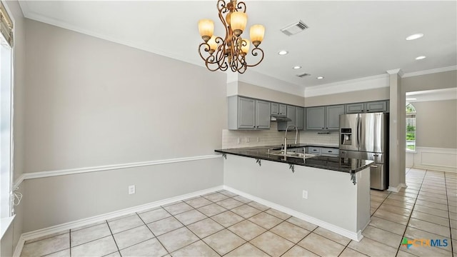 kitchen featuring stainless steel fridge, gray cabinetry, a peninsula, dark countertops, and light tile patterned floors