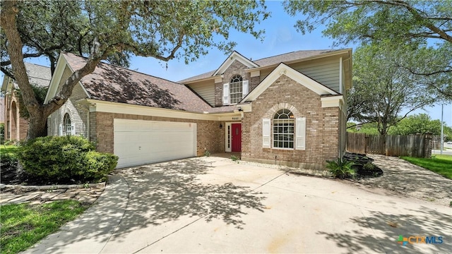 traditional-style home with brick siding, an attached garage, concrete driveway, and roof with shingles