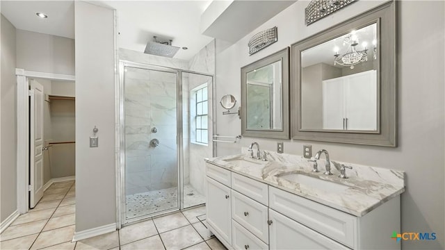 bathroom with a shower stall, double vanity, tile patterned floors, and a chandelier