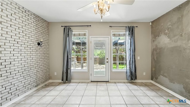 doorway to outside featuring a ceiling fan, an accent wall, brick wall, and light tile patterned floors