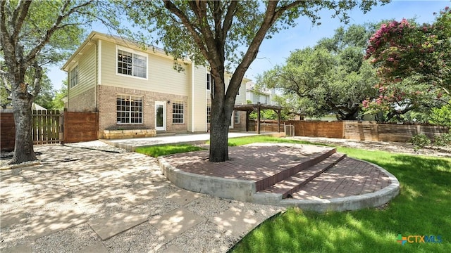 rear view of house with brick siding, a pergola, a patio, and a fenced backyard