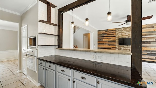 kitchen featuring white oven, ceiling fan, dark countertops, crown molding, and light tile patterned floors