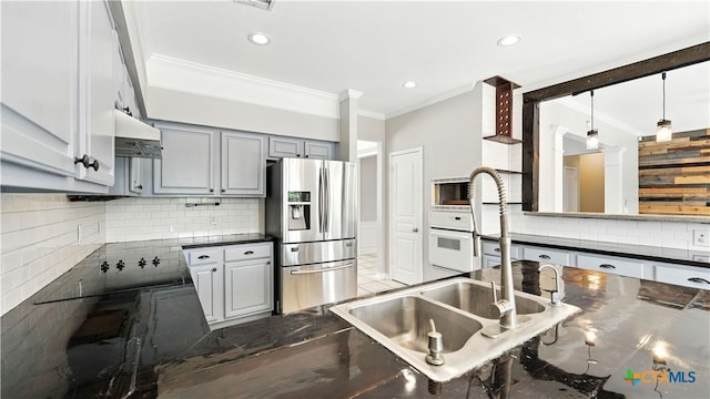 kitchen featuring stainless steel fridge with ice dispenser, ornamental molding, dark countertops, under cabinet range hood, and tasteful backsplash