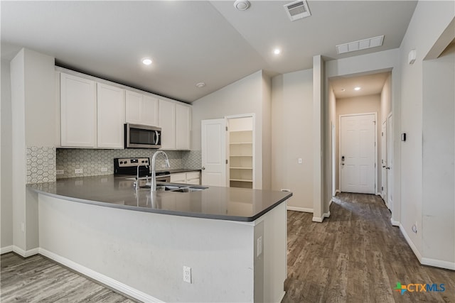 kitchen featuring sink, dark wood-type flooring, tasteful backsplash, white cabinets, and kitchen peninsula