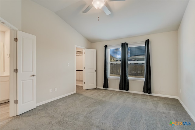 unfurnished bedroom with lofted ceiling, a spacious closet, light colored carpet, and ceiling fan