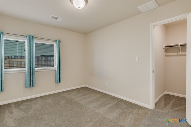 unfurnished bedroom with a spacious closet, a closet, and carpet flooring