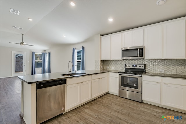 kitchen featuring sink, white cabinetry, light hardwood / wood-style flooring, appliances with stainless steel finishes, and kitchen peninsula