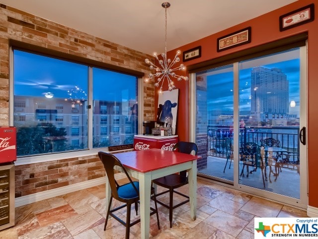 dining area with brick wall and a notable chandelier