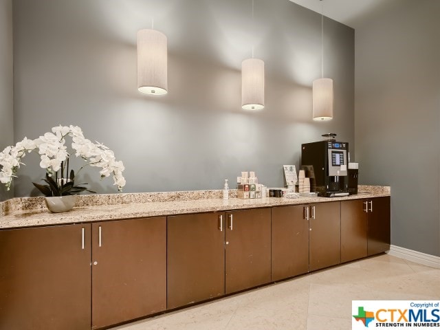 kitchen with light tile patterned floors, decorative light fixtures, and light stone counters