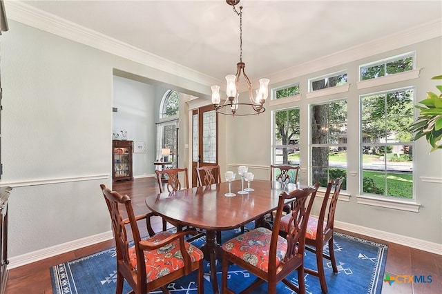dining space with a chandelier, crown molding, baseboards, and wood finished floors