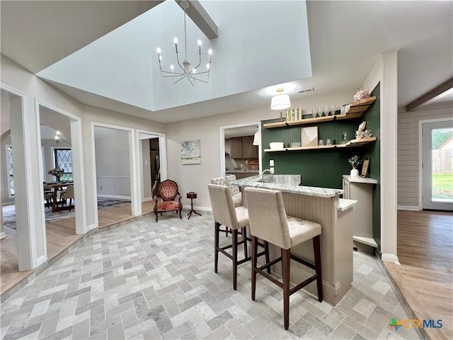 101 Biltmore Dr, Victoria, TX 77904 - kitchen with open shelves, a chandelier, a breakfast bar area, light stone countertops, and pendant lighting