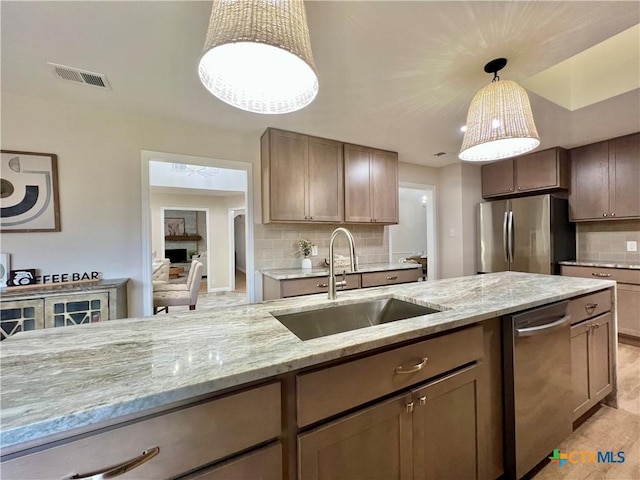 101 Biltmore Dr, Victoria, TX 77904 - kitchen with appliances with stainless steel finishes, backsplash, light stone counters, and hanging light fixtures