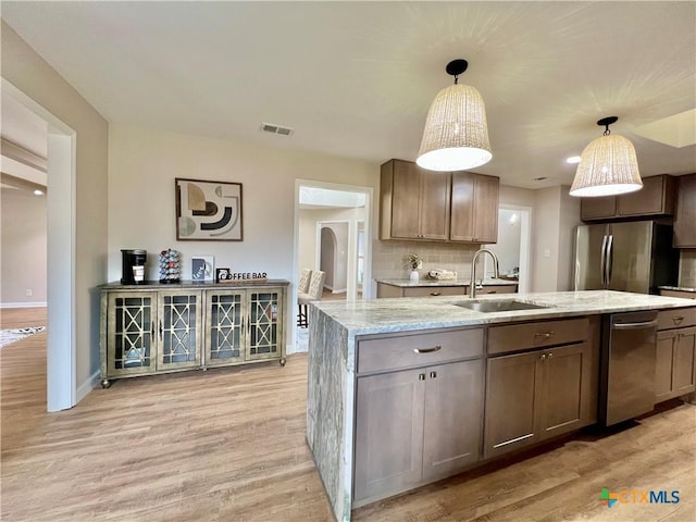 101 Biltmore Dr, Victoria, TX 77904 - kitchen featuring light wood-type flooring, appliances with stainless steel finishes, a center island with sink, and light stone counters