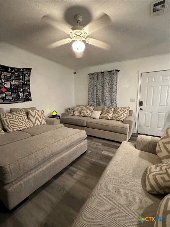 living room with ceiling fan, dark wood-type flooring, and a textured ceiling