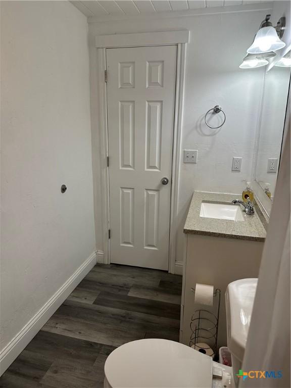 bathroom with toilet, wooden ceiling, wood-type flooring, and vanity