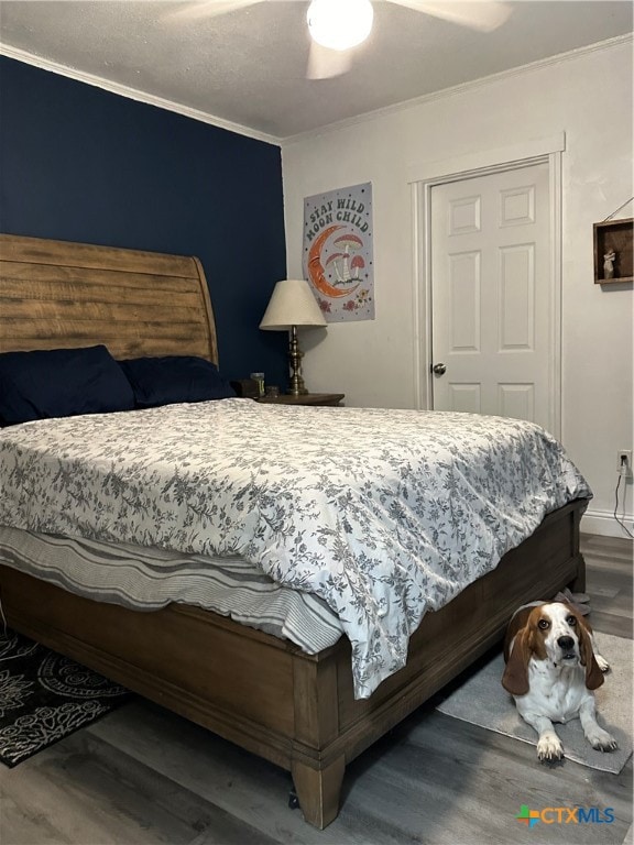 bedroom with ceiling fan, wood-type flooring, and crown molding