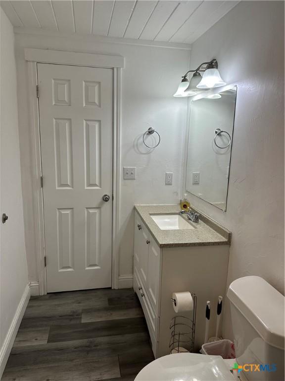 bathroom with toilet, wooden ceiling, wood-type flooring, and vanity