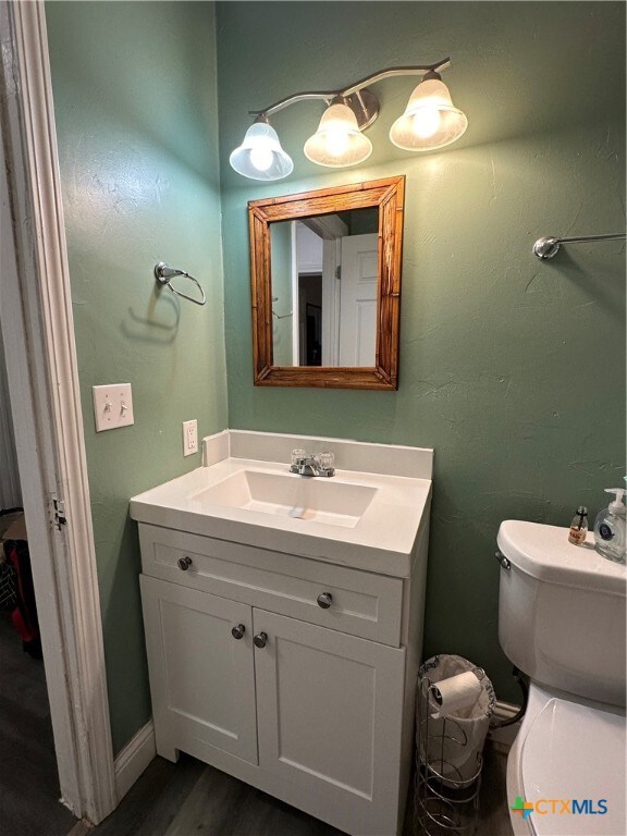 bathroom with hardwood / wood-style flooring, toilet, and vanity