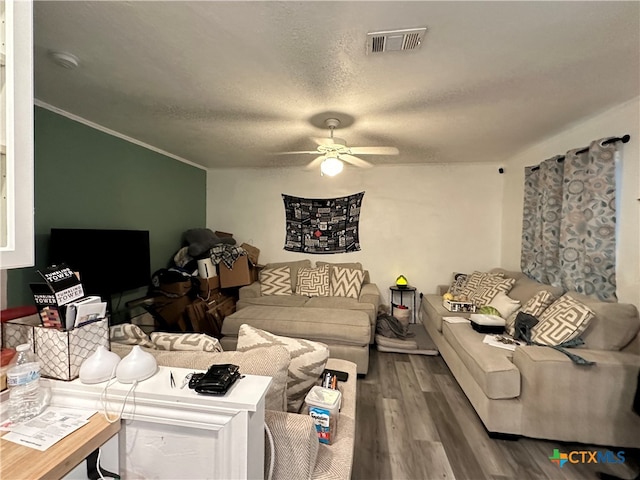 living room with ceiling fan, a textured ceiling, ornamental molding, and hardwood / wood-style floors