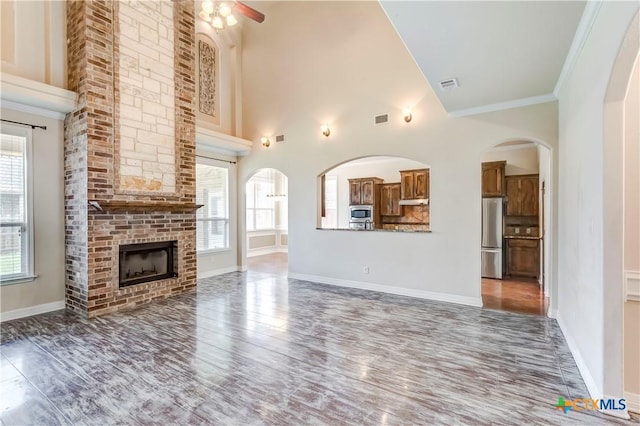 2508 Mugho Dr, Harker Heights, TX 76548 - unfurnished living room featuring wood finished floors, ceiling fan, a high ceiling, a fireplace, and crown molding