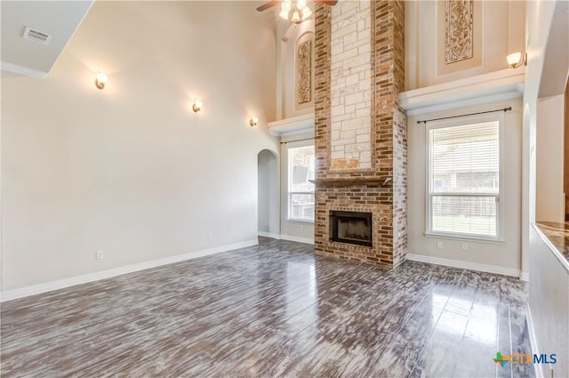 2508 Mugho Dr, Harker Heights, TX 76548 - unfurnished living room with a high ceiling, wood finished floors, ceiling fan, arched walkways, and a brick fireplace
