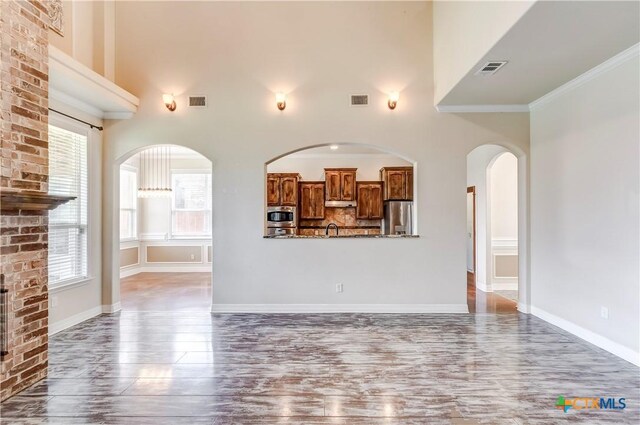 2508 Mugho Dr, Harker Heights, TX 76548 - unfurnished living room featuring wood finished floors, crown molding, and a towering ceiling